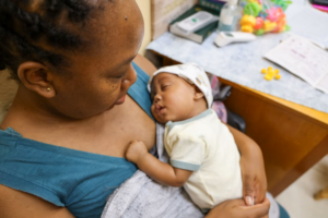 A Bahamian mother holding her newborn baby, symbolizing the elimination of mother-to-child transmission of HIV following WHO certification.