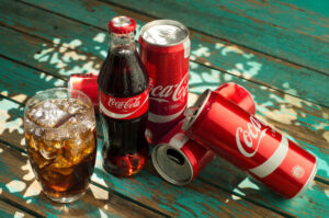 Coca-Cola bottles, cans and PET soft drink packaging illustrating financial pressure from Zimbabwe’s sugar tax on beverage companies.