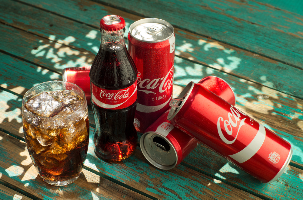 Coca-Cola bottles, cans and PET soft drink packaging illustrating financial pressure from Zimbabwe’s sugar tax on beverage companies.