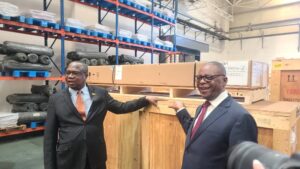 Finance Minister Mthuli Ncube and Health Minister Douglas Mombeshora pose beside a newly delivered radiotherapy machine destined for Zimbabwe's cancer treatment programme.