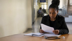 Young Zimbabwean woman reviewing legal and medical documents related to termination of pregnancy after rape.